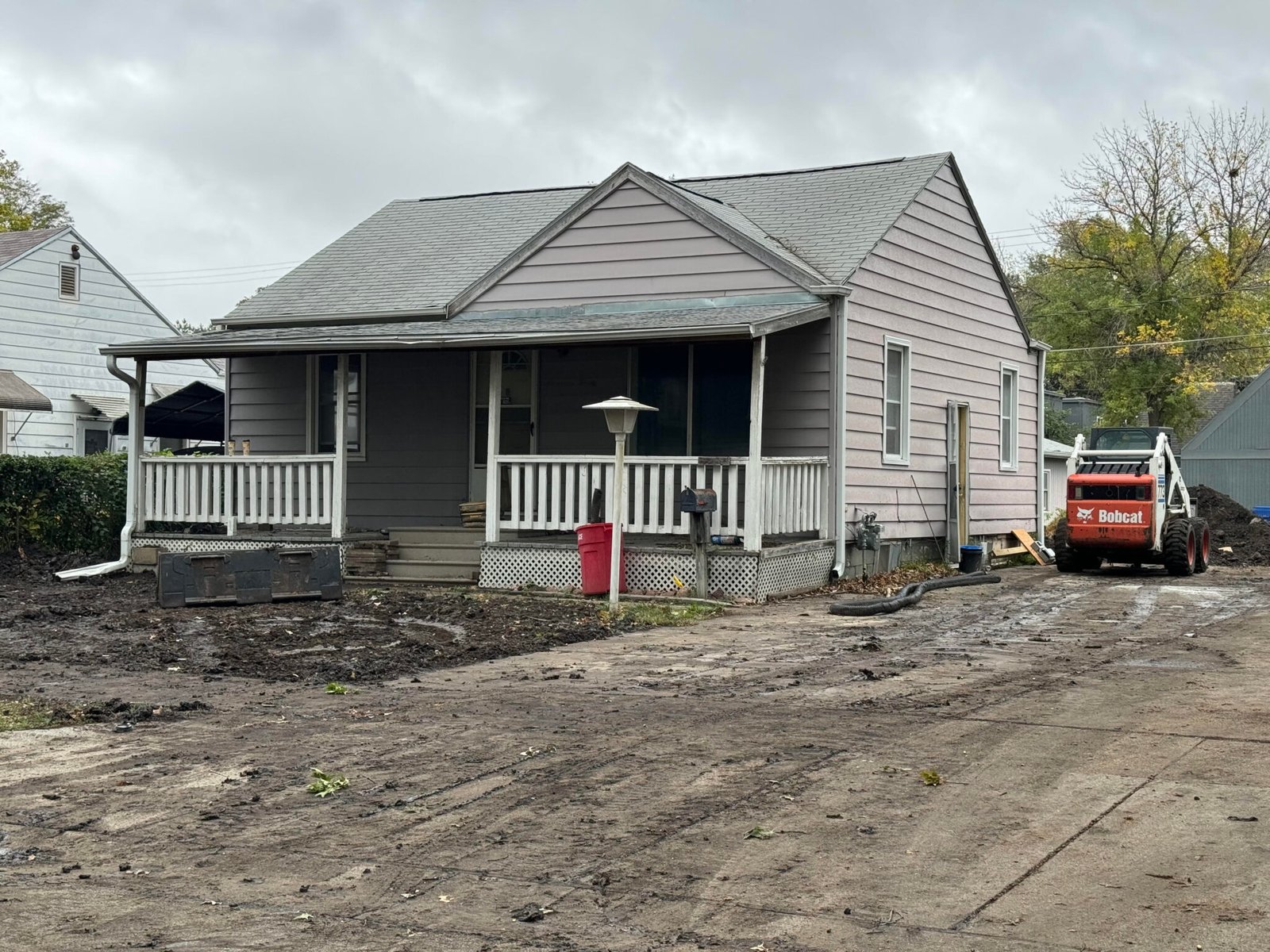 A Lincoln house mid-renovation, with a skid steer regrading the torn-up front yard and driveway.