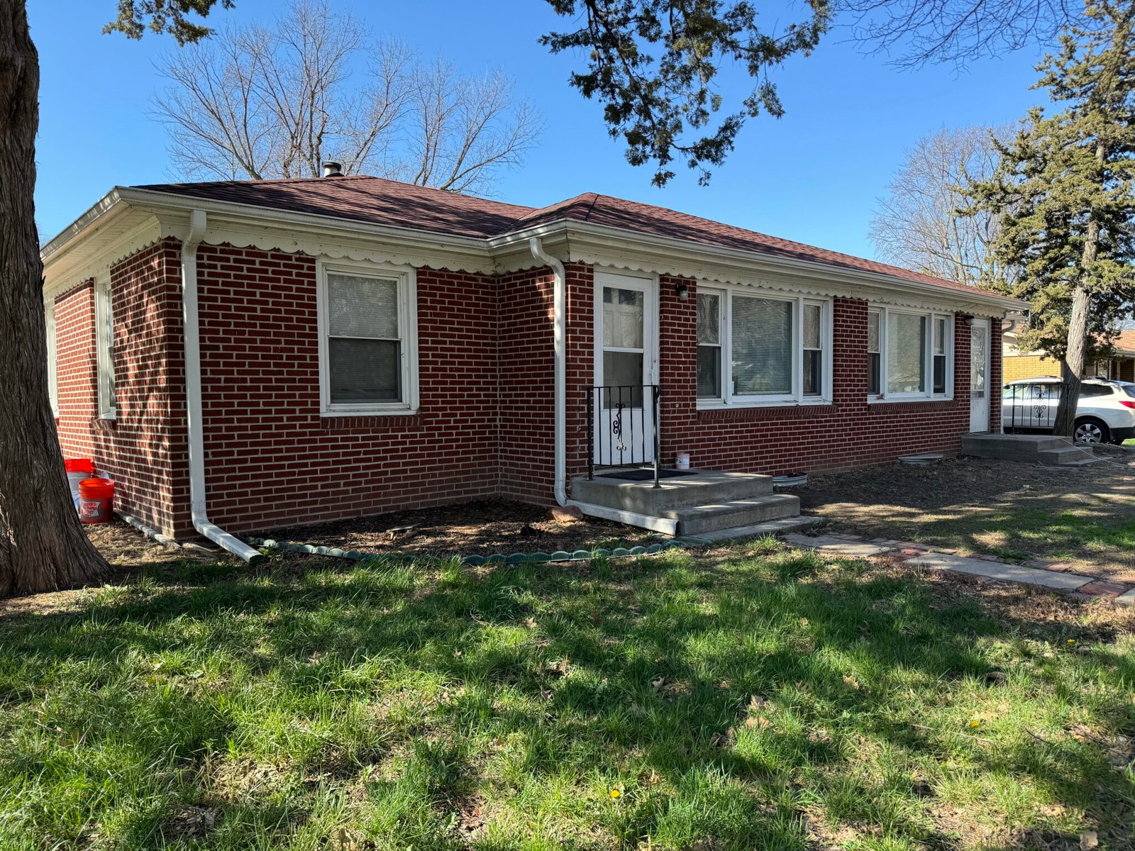 A red brick single-storey ranch house in Lincoln with a mature tree in the front yard.